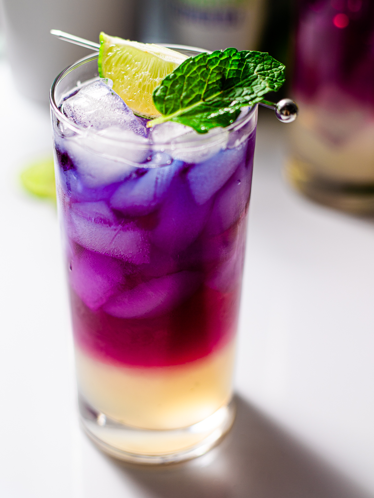 butterfly pea flower tea mocktail with lime garnish before being stirred