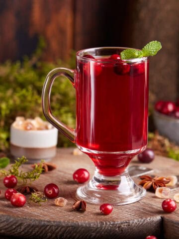 A glass with cranberry mors surrounded by cranberries
