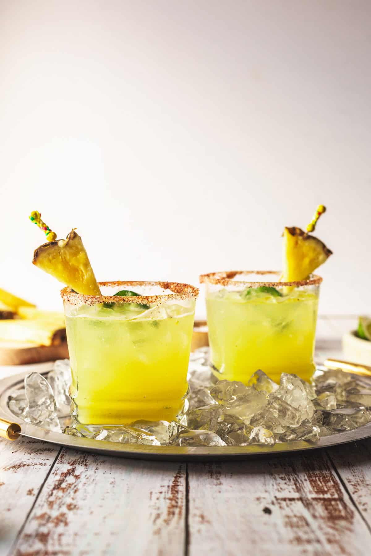 Two glasses of pineapple margarita on a tray.