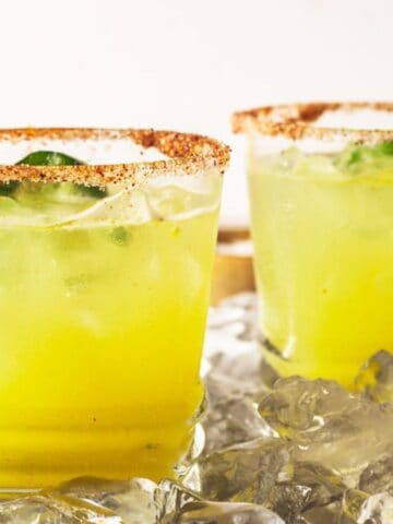 Two spicy margaritas with a pineapple garnish on a tray.