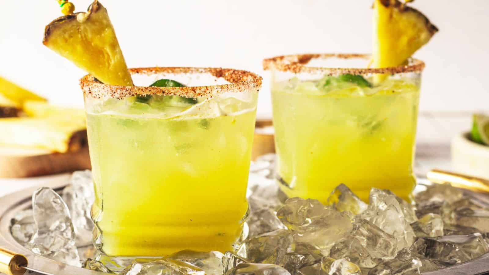 Two spicy margaritas with a pineapple garnish on a tray.