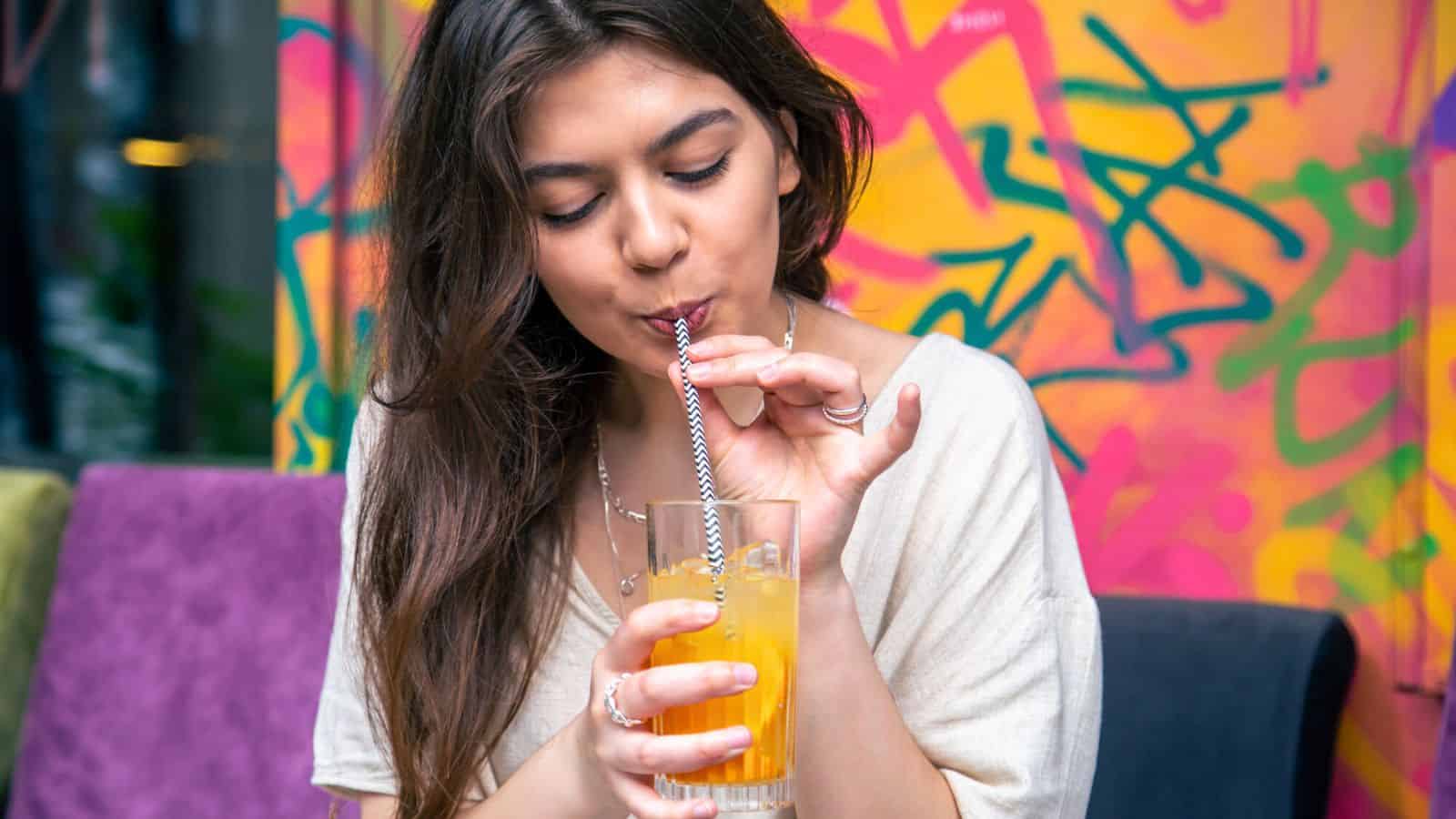 Woman drinking sparkling lemonade from a tall glass