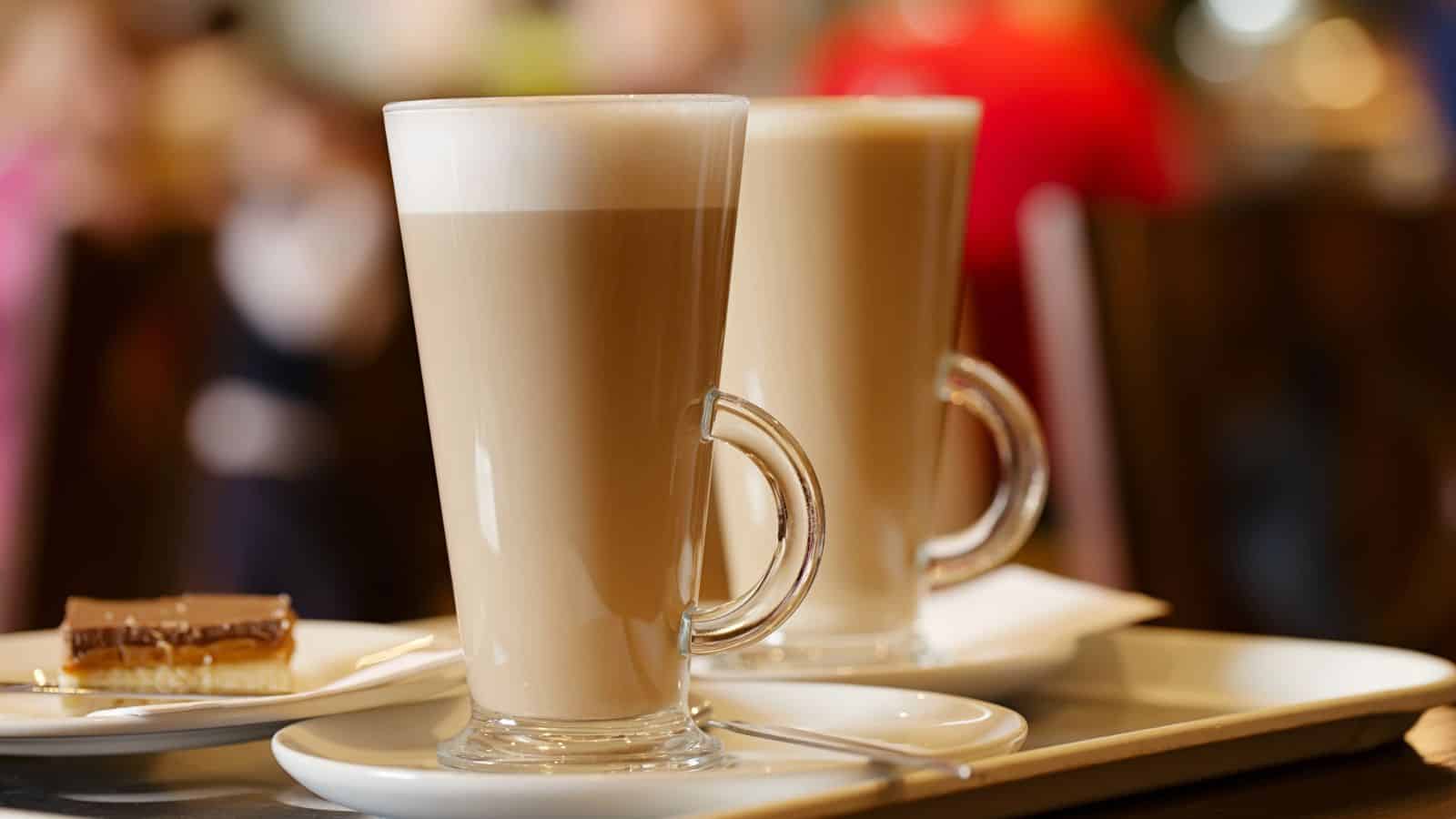 Two tall glasses of Caff&egrave; Latte on top of small plates