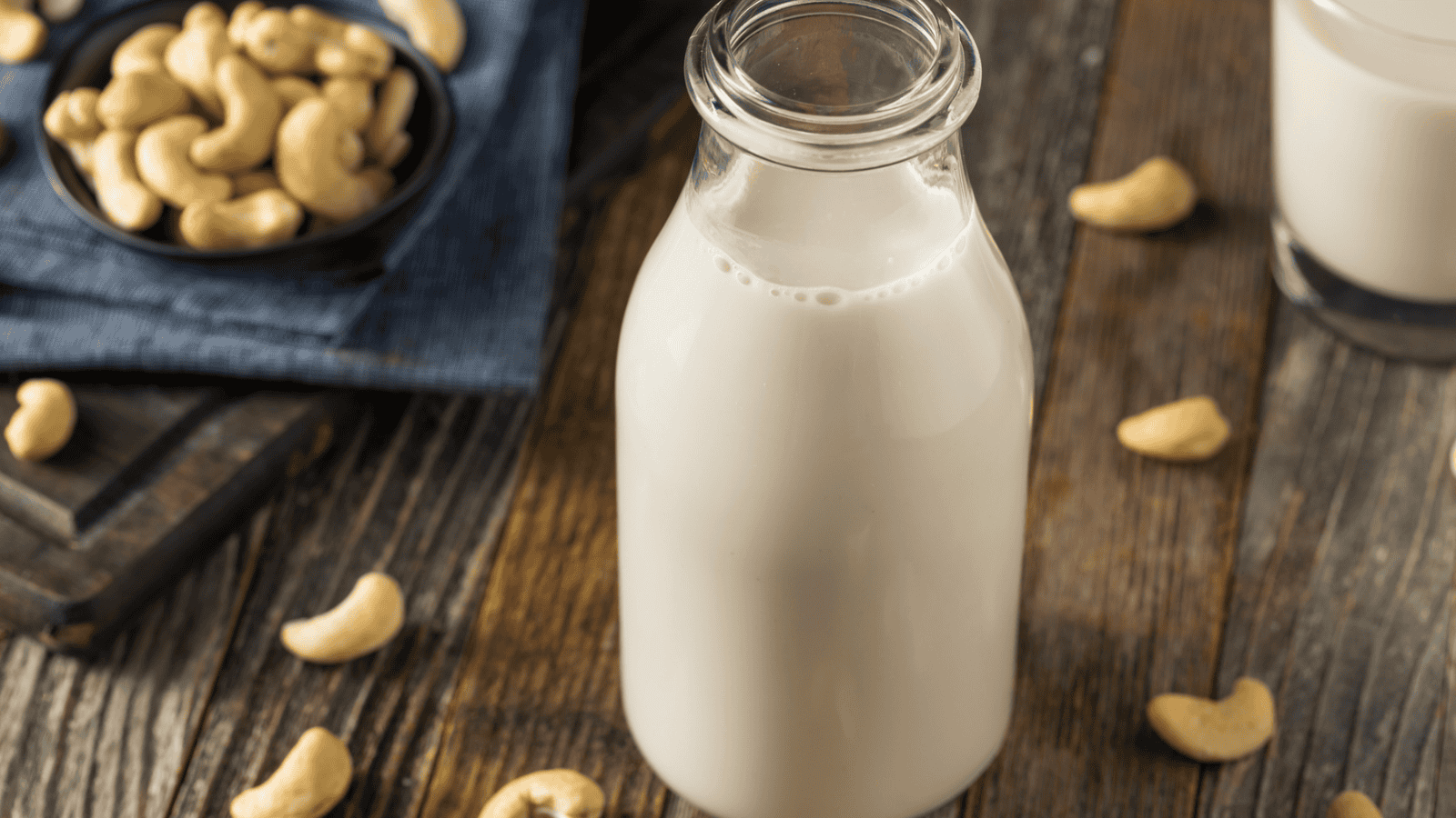 Decanter of cashew milk with some cashew nuts in the background