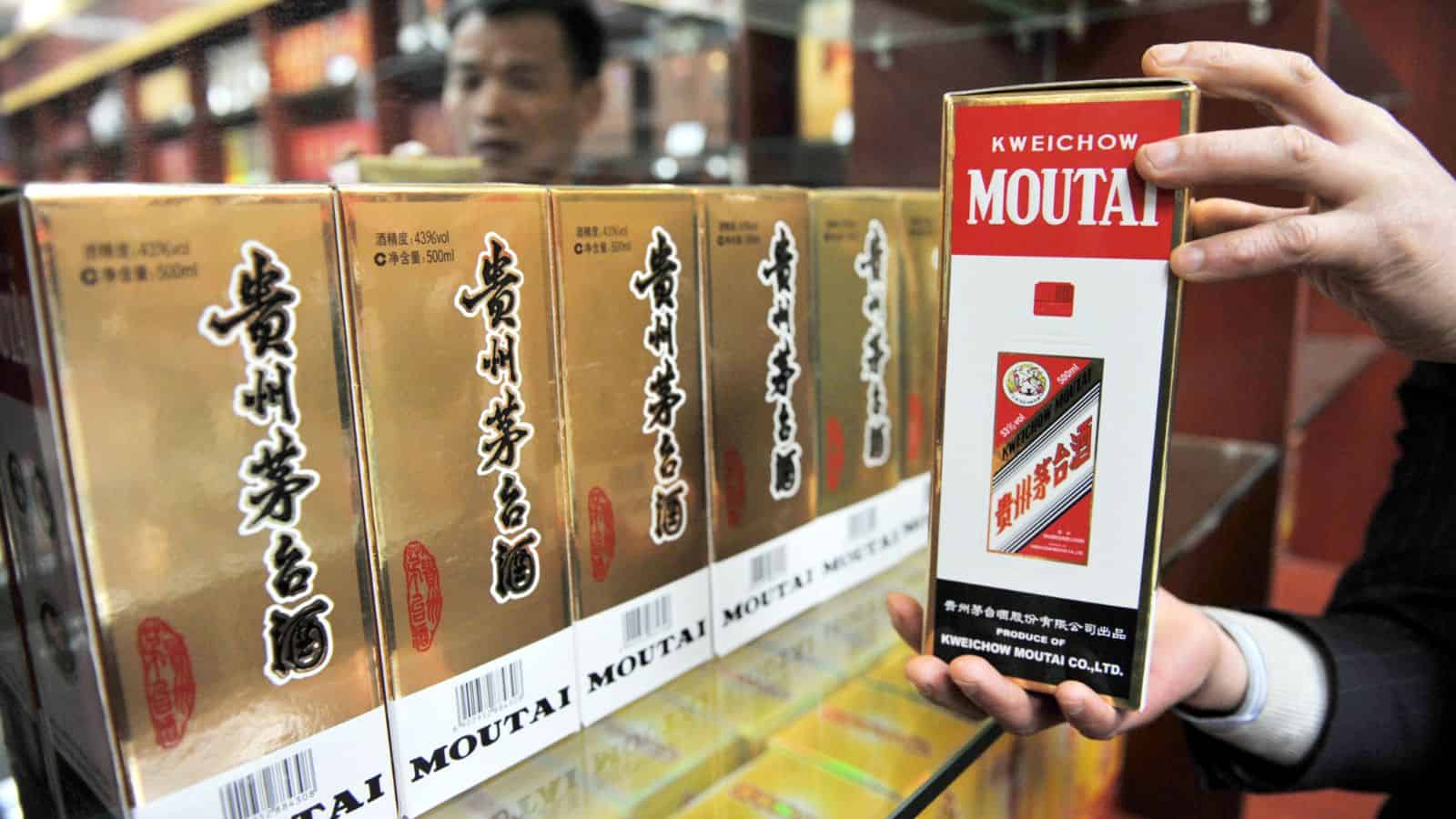 Person holding moutai in their hands. In the background, there are several boxes of moutai. 