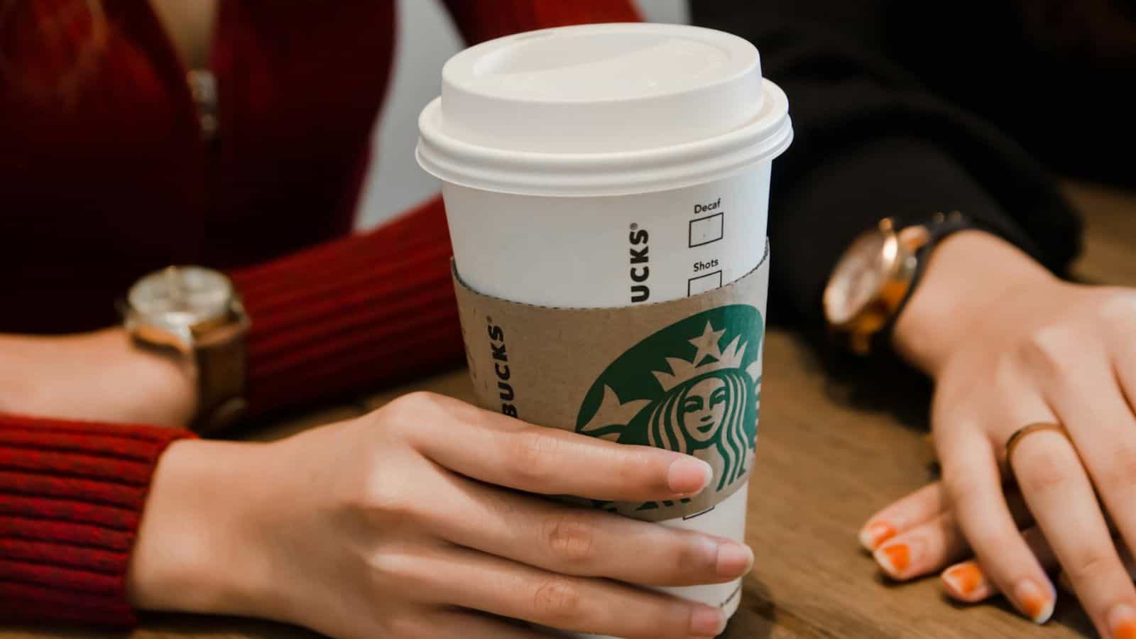 Hand holding a cup of Starbucks coffee