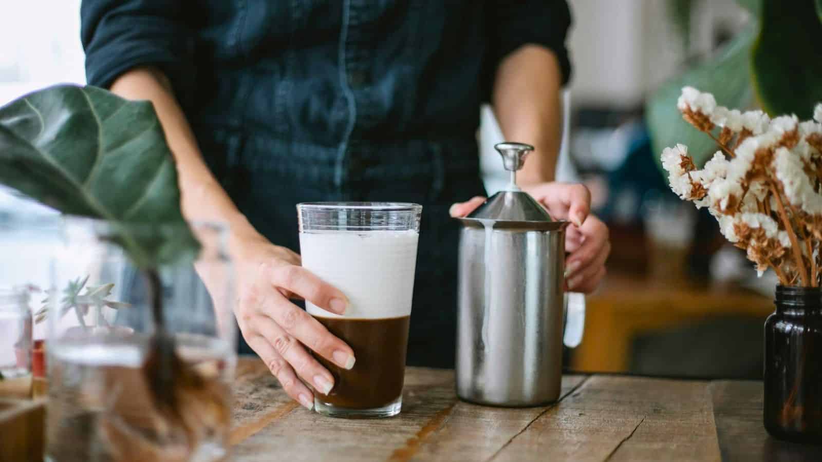 Barista holding a glass of coffee with foam