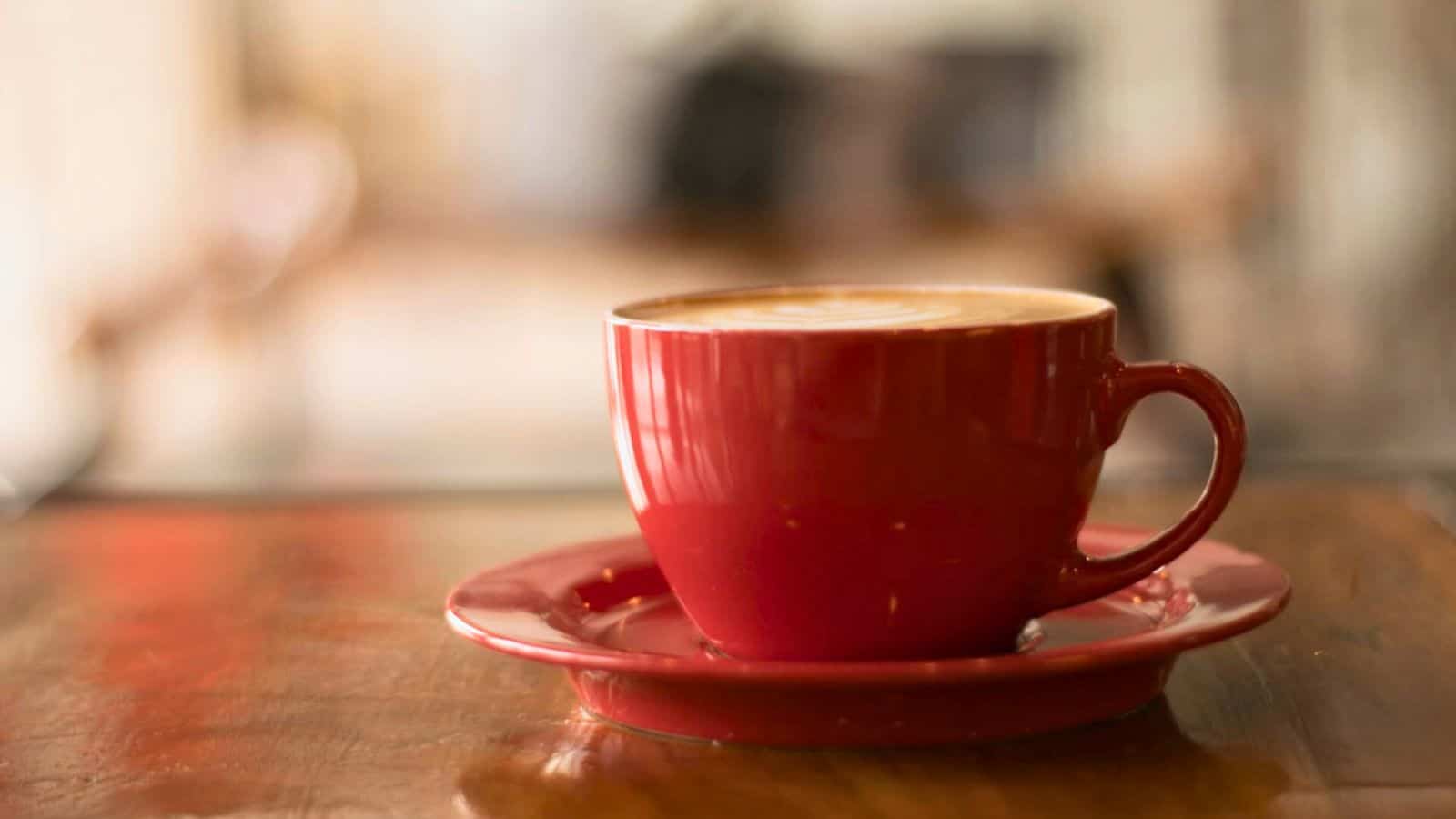 A cup of coffee placed on a plate coaster on top of a table