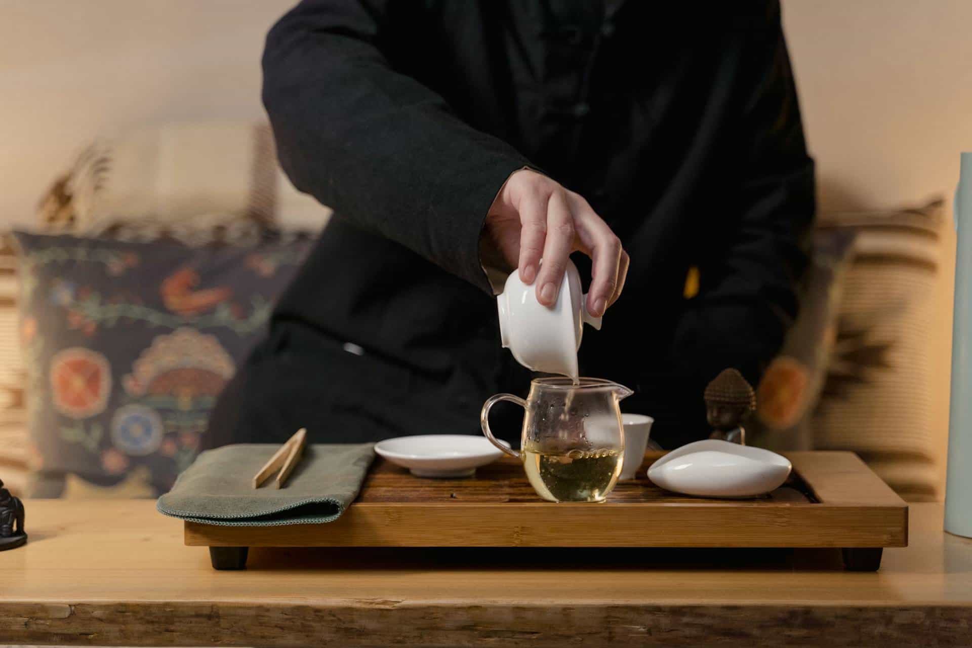 Person pouring green tea into cup.