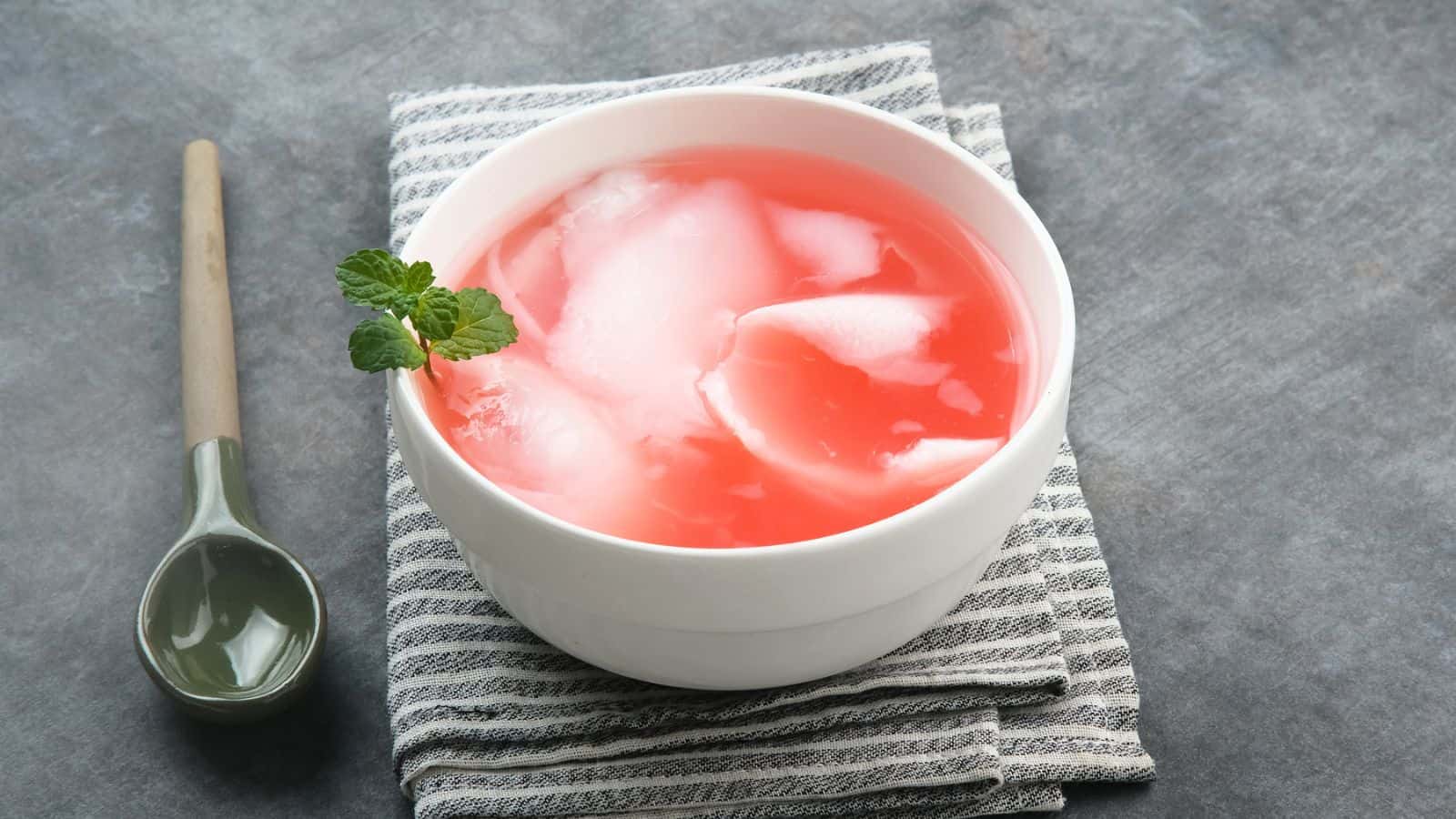A bowl of Es Kelapa Muda placed on top of a tablecloth with a spoon on the side