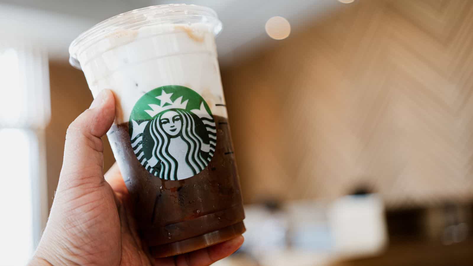A hand holding a cup of Starbucks coffee