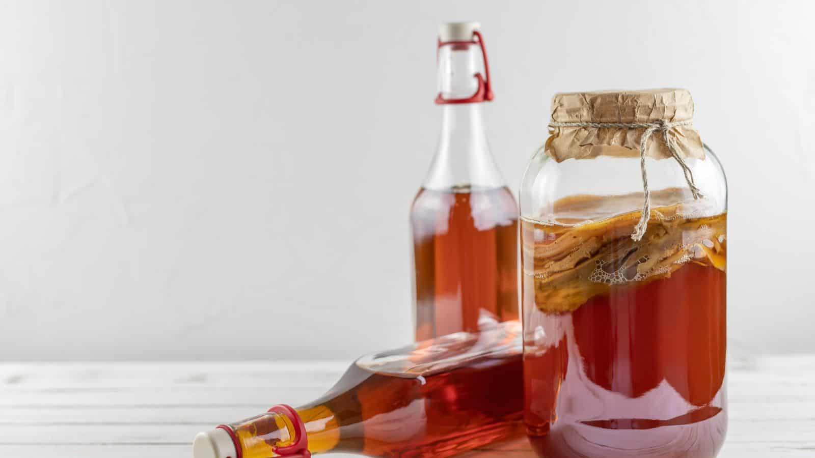 Three containers of kombucha are on a white surface. 