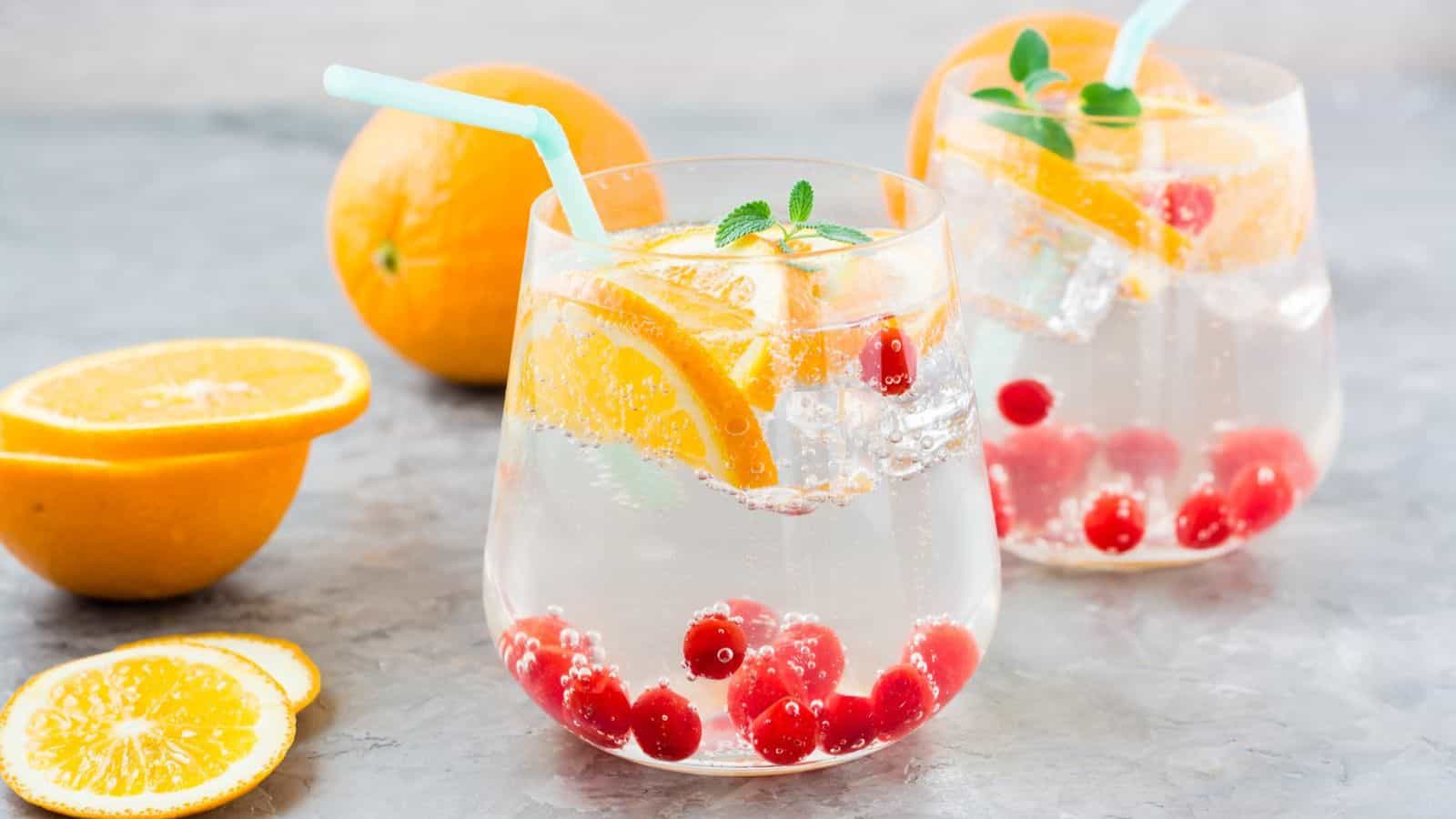 Naturally flavored seltzers in two glasses with infused fresh fruits