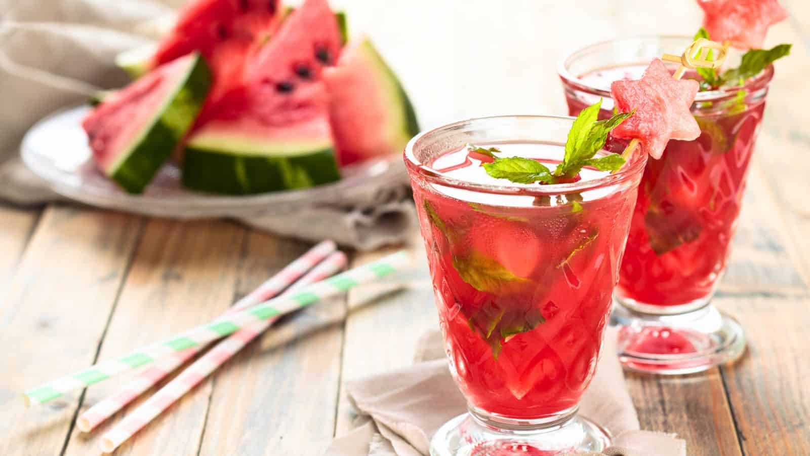 Two glasses of watermelon juice with sliced watermelons on a plate in the background
