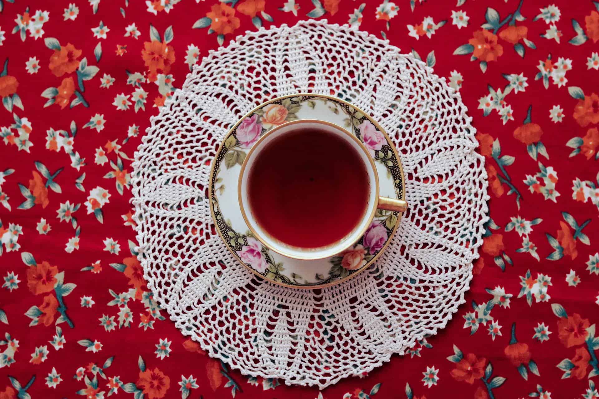 Cup of tea on a doily on red background.