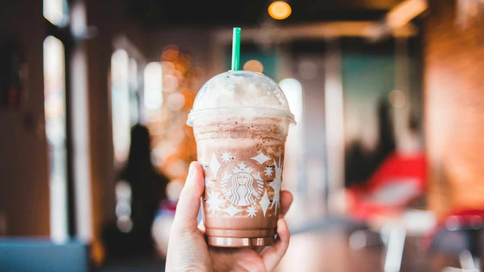 Hand holding plastic Starbucks cup of frappuccino