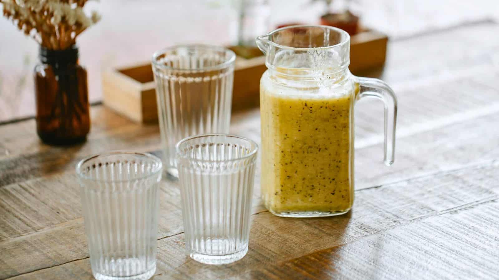 Banana smoothie in a container with three glasses