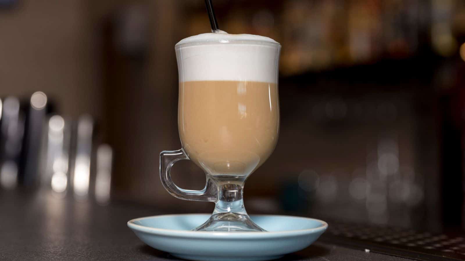 Glass of vanilla latte placed on top of small plate coaster