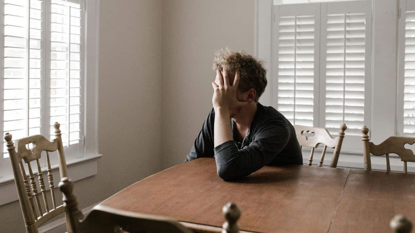 Man who seems like in a bad mood sits down and gazes outside 