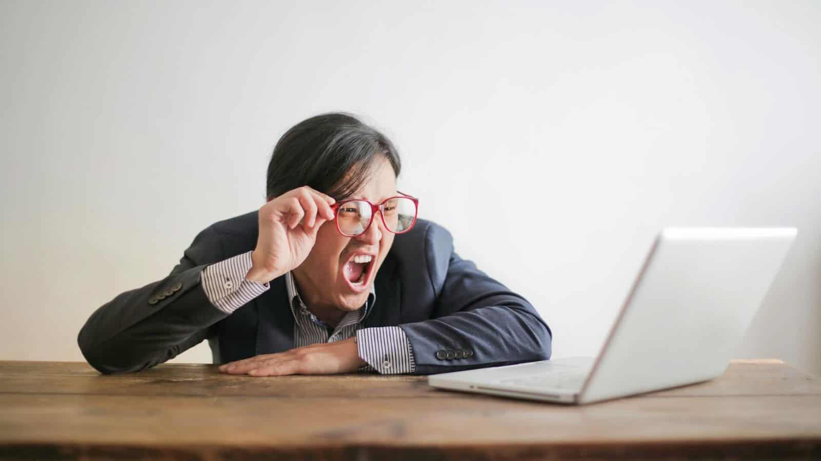 Man with glasses scream at his laptop