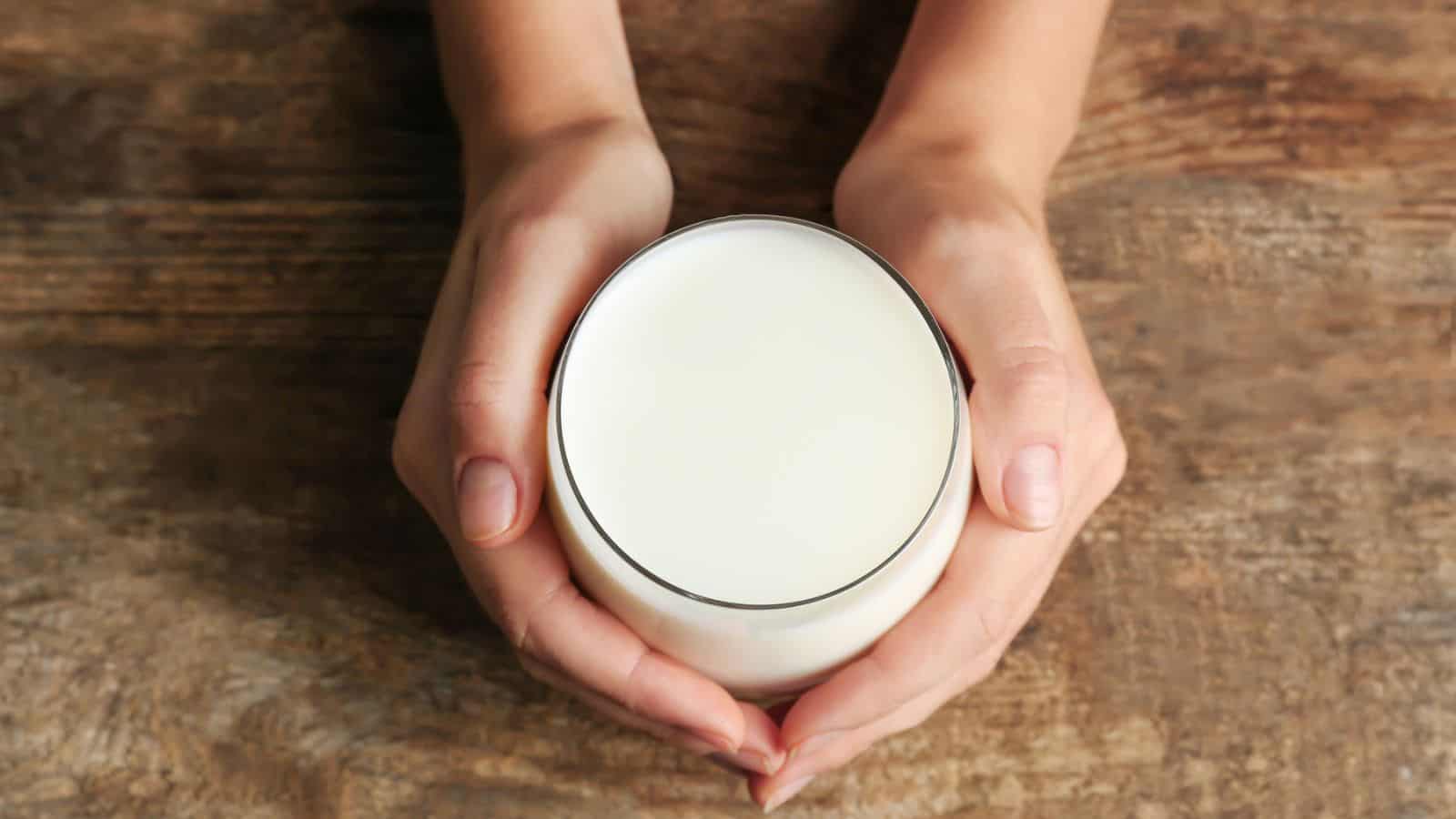 Hands holding a glass of milk