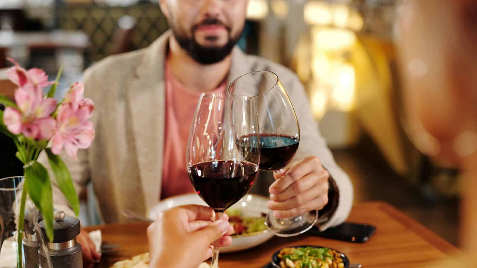 A couple clinking their red wine glasses together
