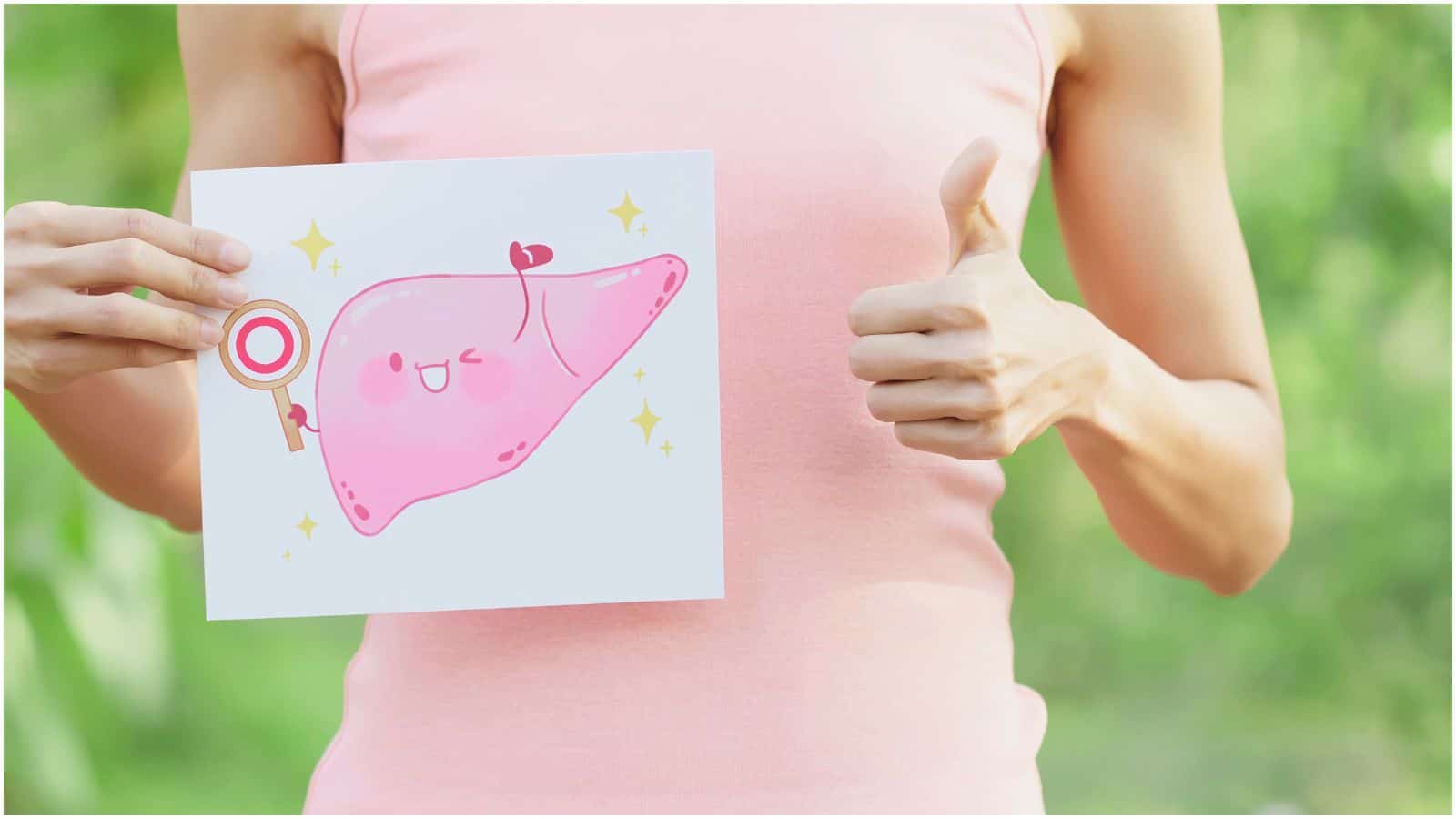 A person in a pink tank top holds a drawing of a smiling liver with a key, while giving a thumbs-up with their other hand. The background is blurred greenery&mdash;a reminder of the benefits when you stop drinking alcohol.