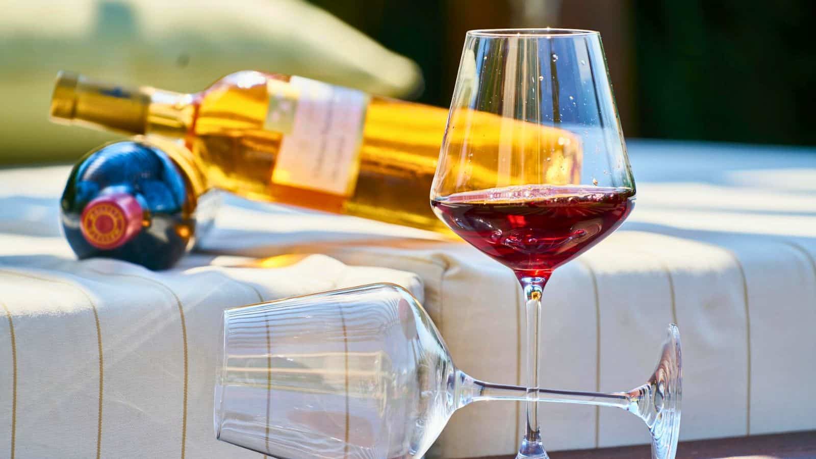 Bottle of wine and two glasses, the other one half full while the other one is empty