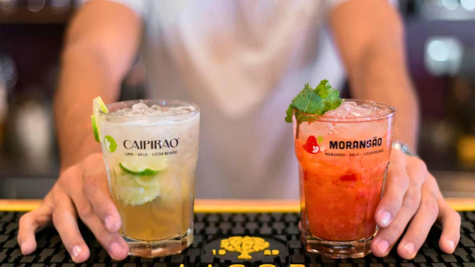 Bartender holding two drinks made out of different ingredients