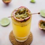 Side view of passionfruit mocktail with lime wedges around