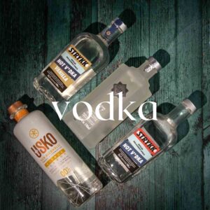Four bottles of alcohol-free vodka substitutes are arranged in a cross pattern on a dark green wooden surface. The brands include Stryyk Not Vodka, Stryyk Not Vanilla Vodka, Clean Co Clean V, and Usko Nordic Botanical Spirit. The word "vodka" is superimposed in white lowercase text.