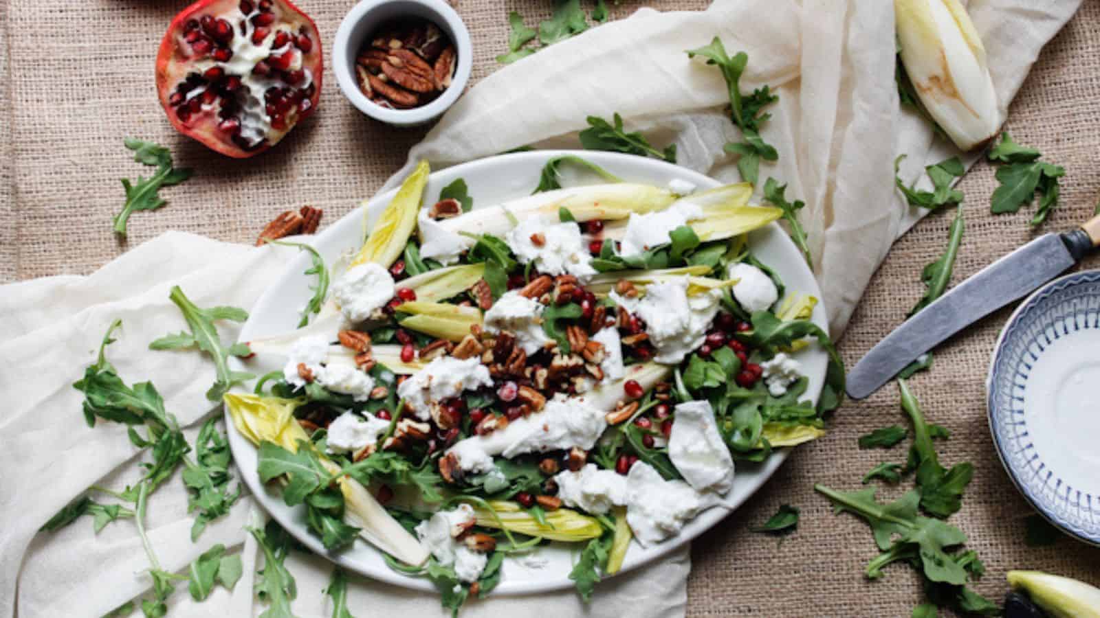 Side view of arugula salad on platter with pomegranates.