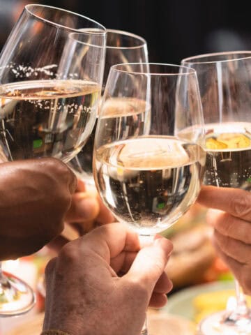 Five people clinking glasses of refreshing white wines in a celebratory toast.