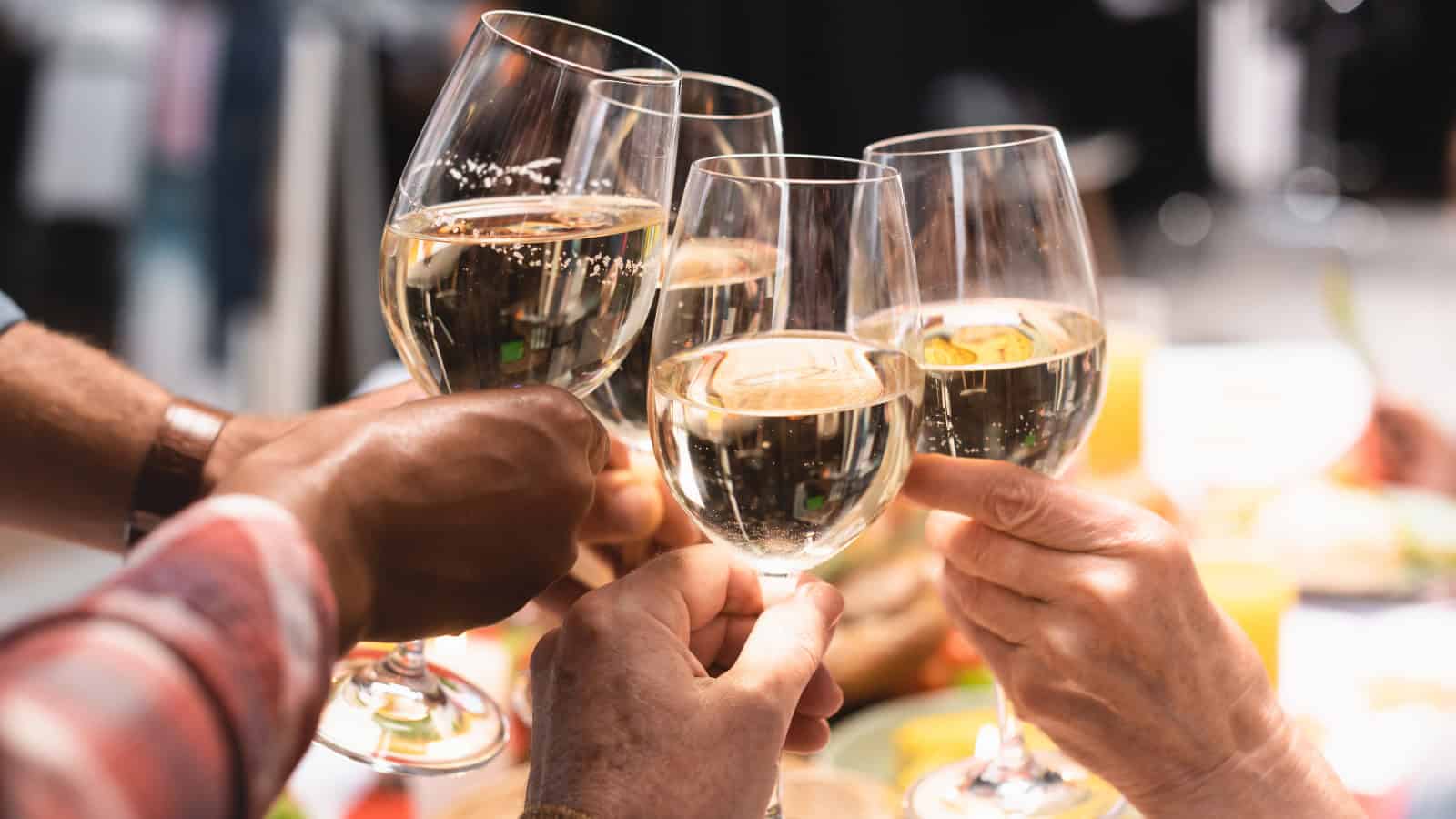 Five people clinking glasses of refreshing white wines in a celebratory toast.
