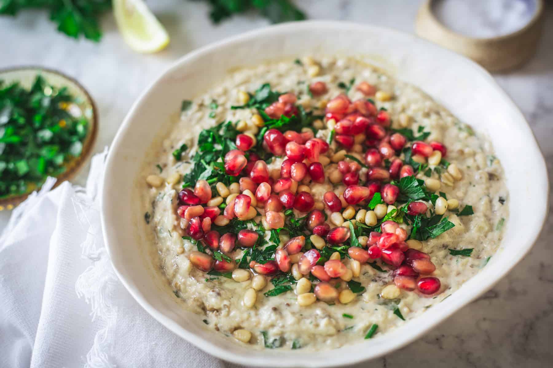 Baba ganoush on a plate with pomegranate seeds, parsley.