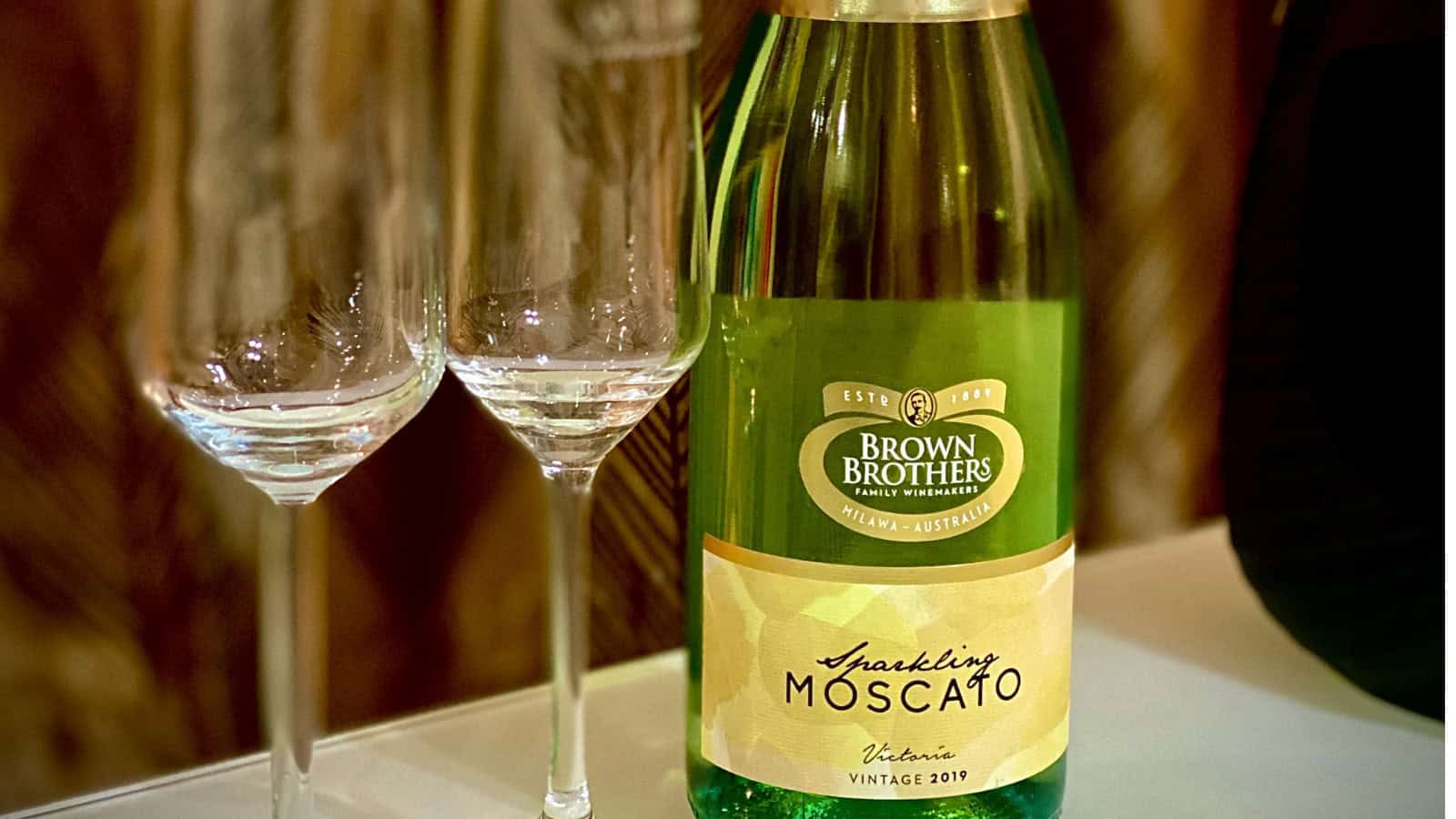 A bottle of Sparkling Moscato with two wine glasses behind it.