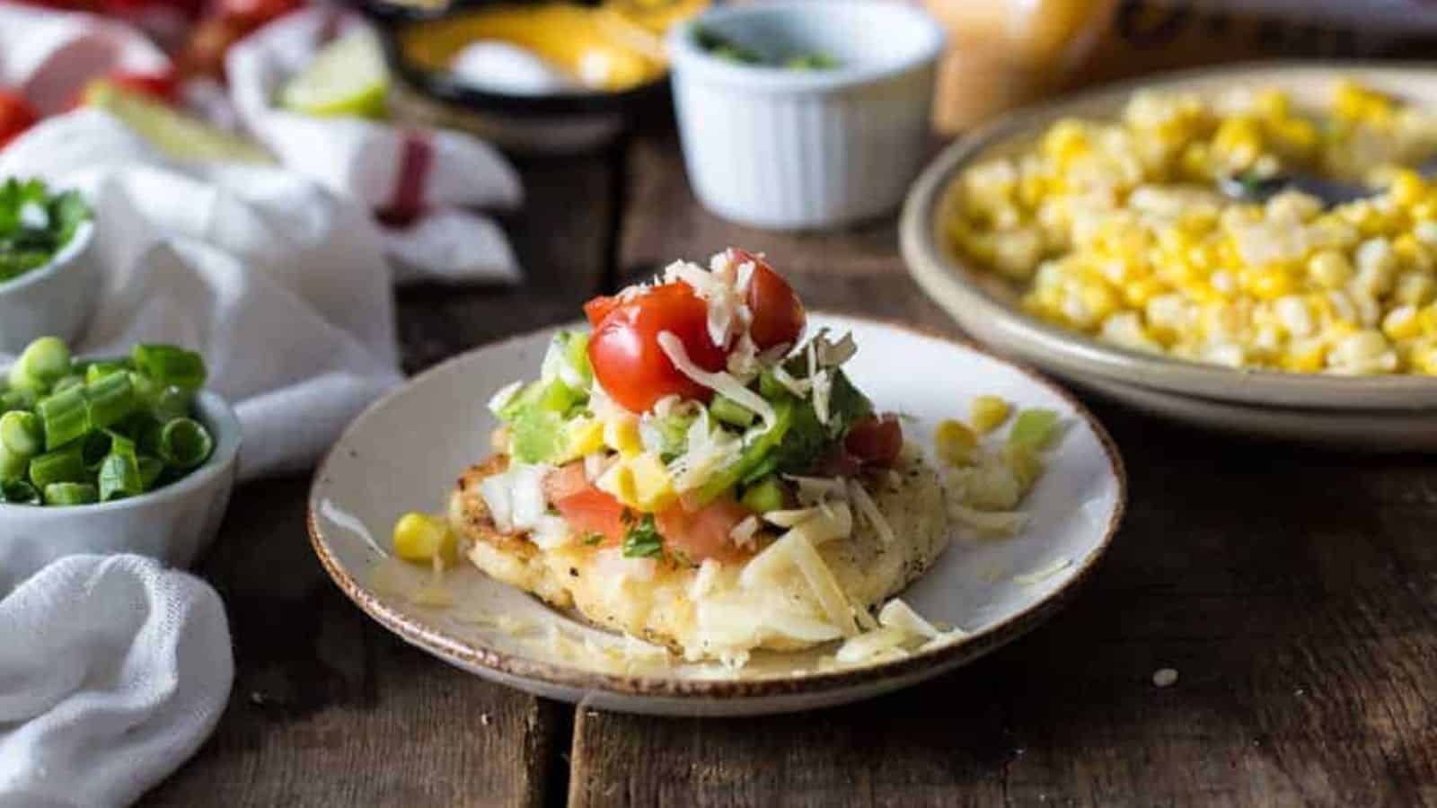 Cheese arepa on a plate with toppings.