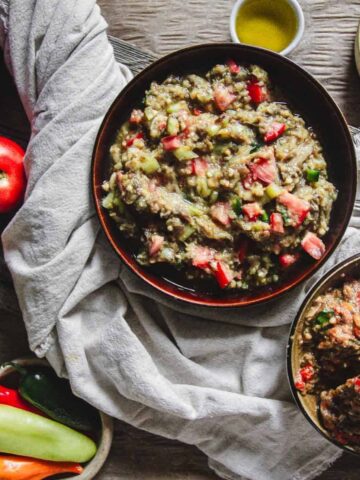 A rustic table setting features bowls of eggplant and tomato dip.