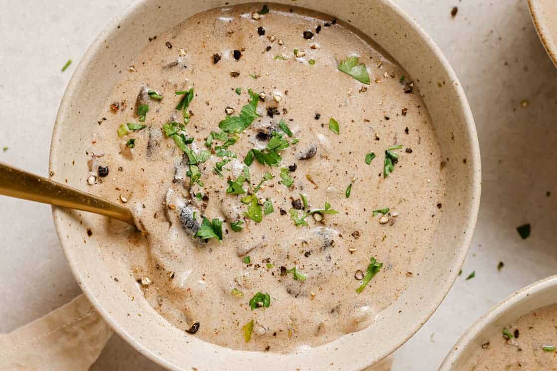 A bowl of Hungarian mushroom soup with a gold spoon.