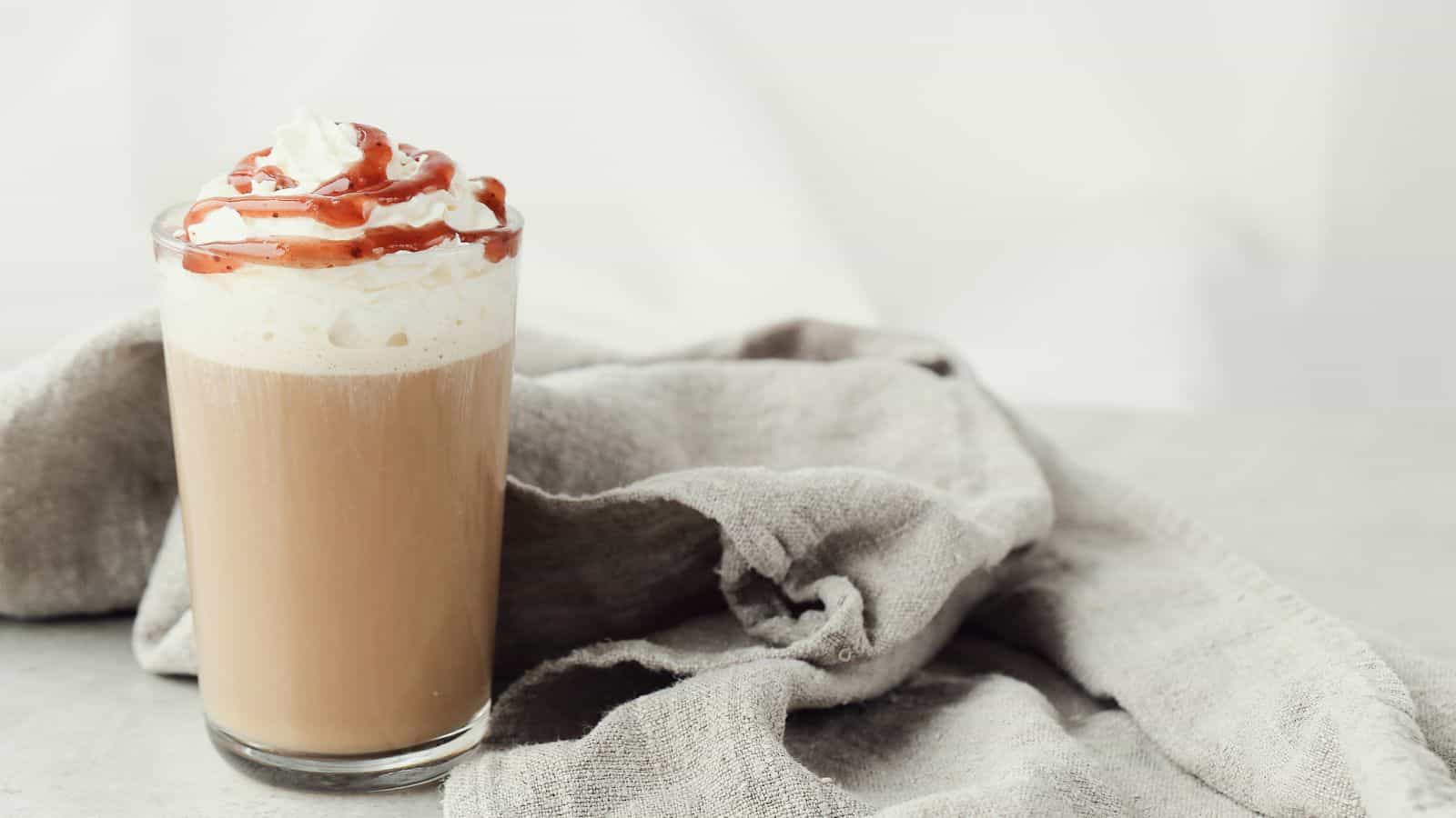 An image of a glass of coffee with whipped cream and toffee nut syrup drizzle.