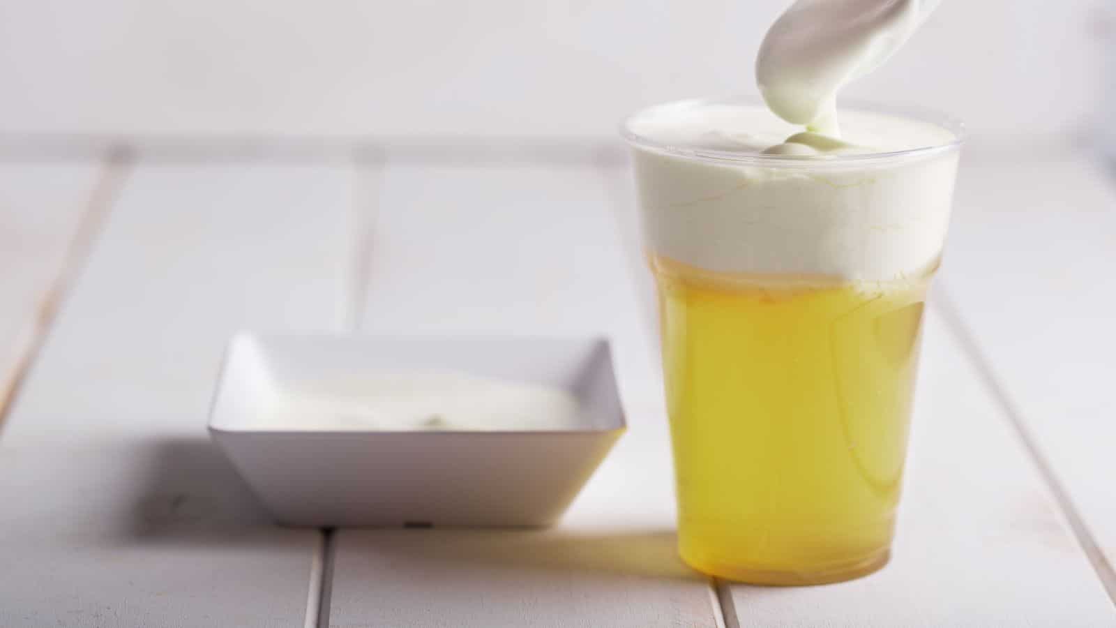 An image of yellow juice with white foam on top.