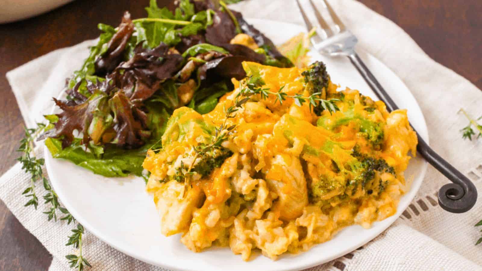 Chicken broccoli casserole on a white plate next to a green side salad.