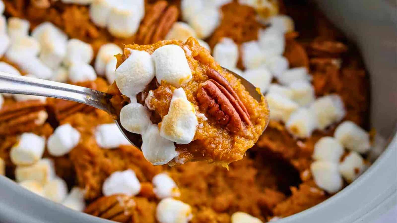 Crock pot with sweet potato casserole with pecans and marshmallows.