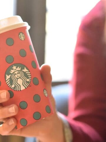 An image of a girl holding a Christmas-themed Starbucks cup.