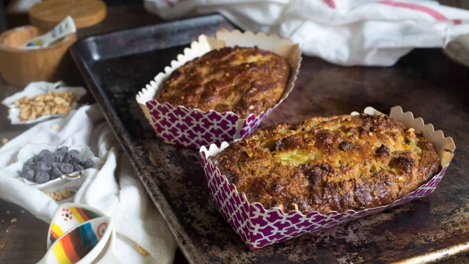 Two slices of chocolate banana bread with loaf in background.