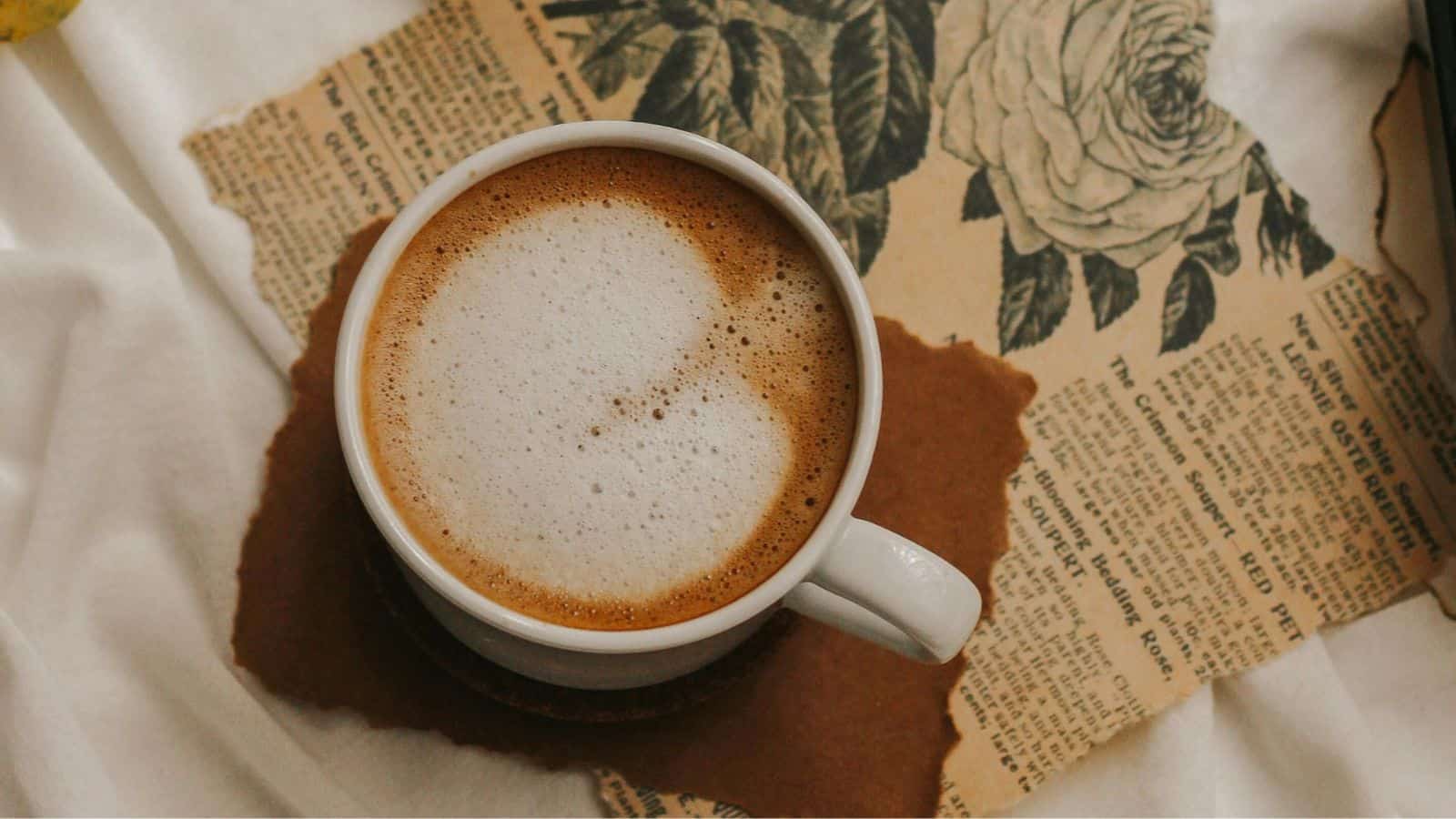 An overhead image of holiday spice flat white on a table with vintage paper.