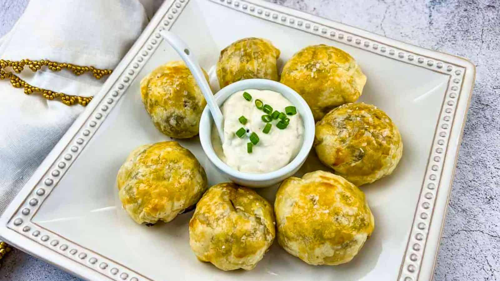 Beef Wellington Bites on a white plate with sauce in the middle.