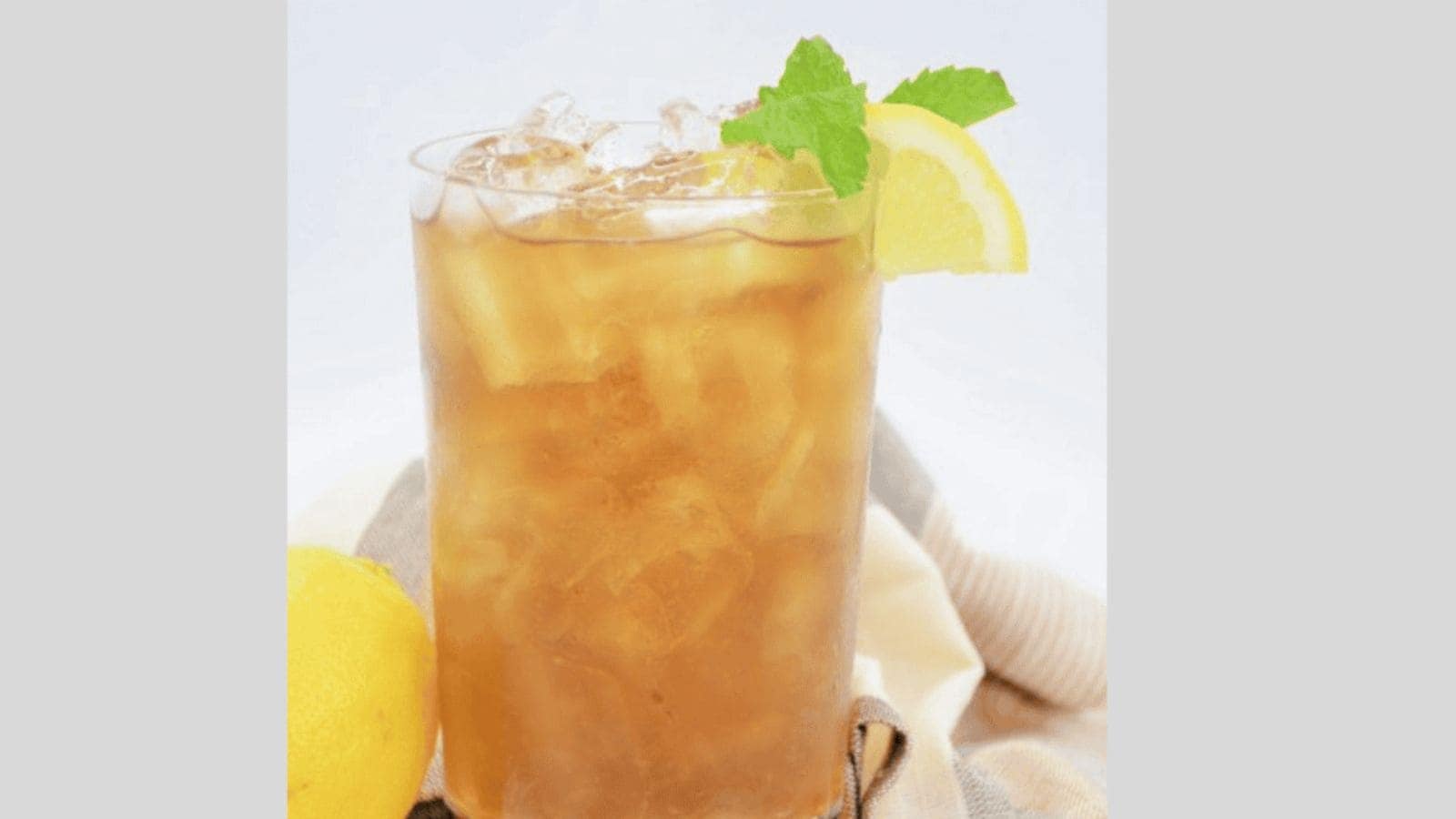 A long island iced tea garnished with lemon and mint.