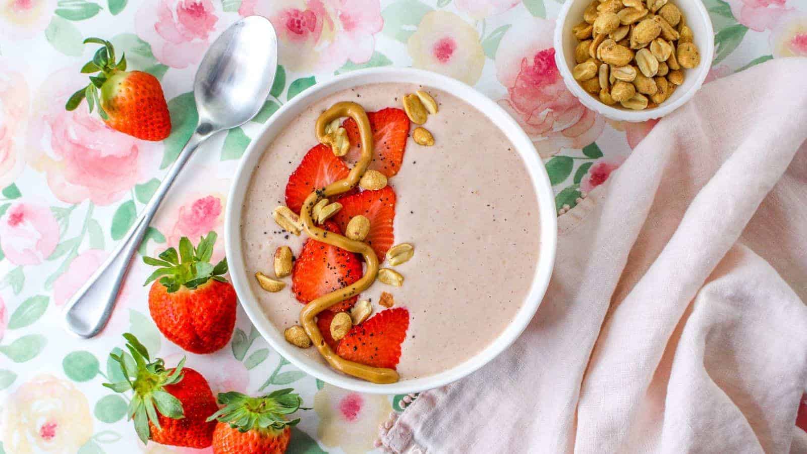 Smoothie  topped with strawberries, peanuts, and peanut butter swirl in bowl.