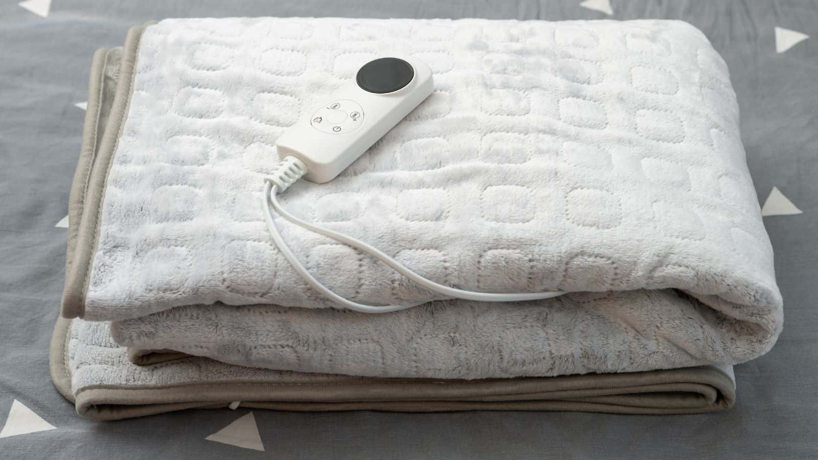 A folded heated throw blanket with its controller visible and placed on top of it.